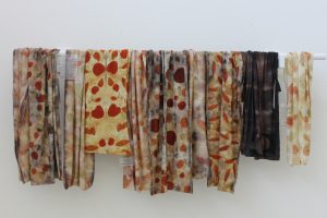 Eco-dyed fabrics hanging from a rail